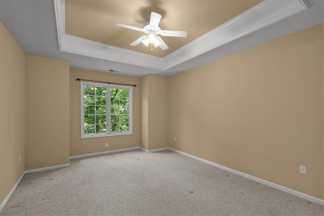 unfurnished room featuring a tray ceiling, crown molding, ceiling fan, and light colored carpet