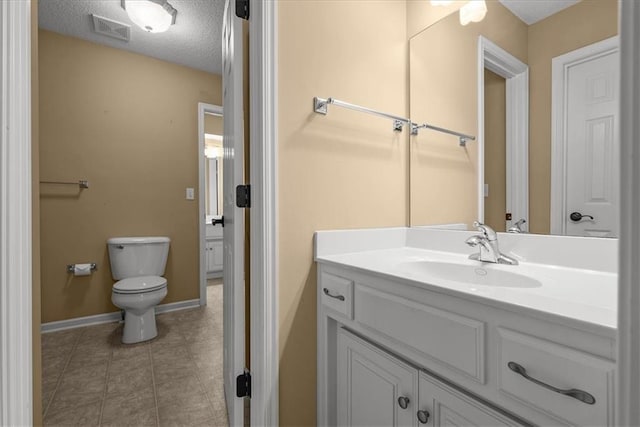 bathroom featuring tile patterned floors, vanity, a textured ceiling, and toilet