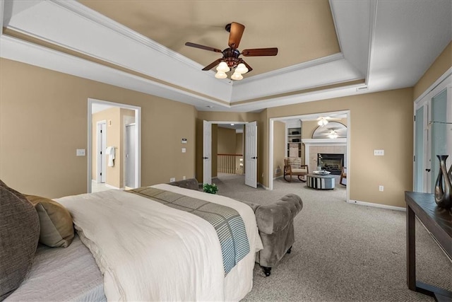 bedroom with light carpet, a tile fireplace, a raised ceiling, and ceiling fan