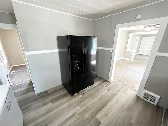 kitchen with ceiling fan, black refrigerator with ice dispenser, and light hardwood / wood-style floors