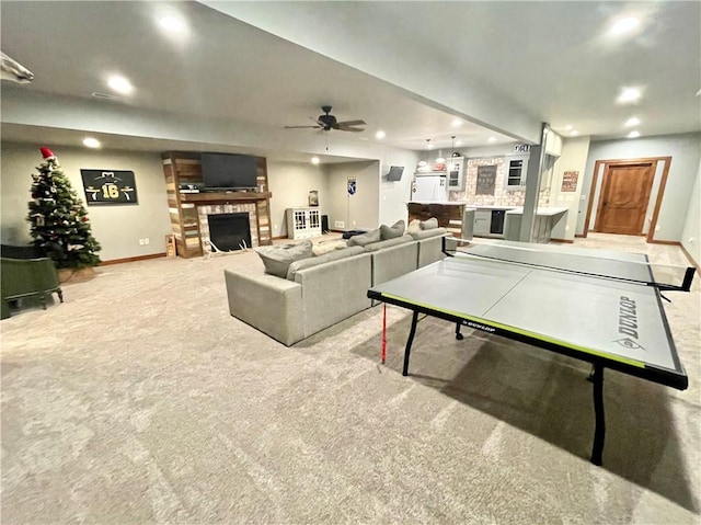 rec room featuring light carpet, a brick fireplace, and ceiling fan