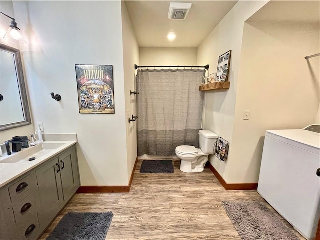 bathroom featuring washer / clothes dryer, a shower with shower curtain, hardwood / wood-style floors, vanity, and toilet