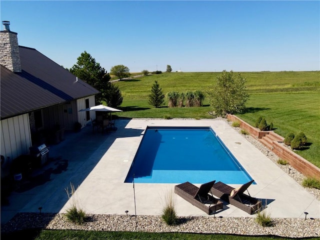 view of swimming pool with a rural view, a lawn, and a patio