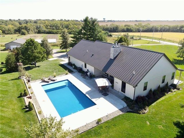 view of pool featuring a patio, a yard, and a rural view