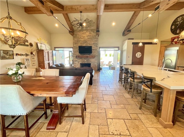 dining room featuring beamed ceiling, a fireplace, high vaulted ceiling, and a wealth of natural light