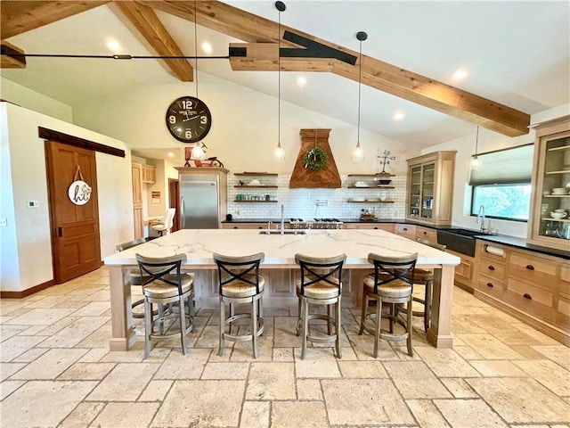 kitchen featuring sink, beam ceiling, a kitchen bar, hanging light fixtures, and a spacious island