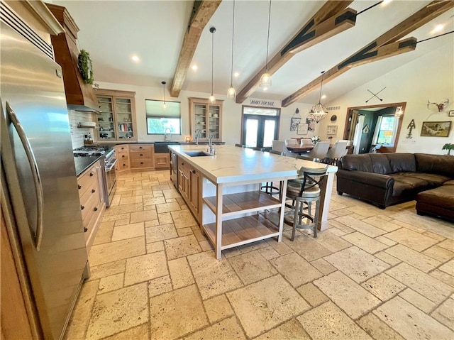 kitchen featuring hanging light fixtures, sink, a center island with sink, appliances with stainless steel finishes, and lofted ceiling with beams