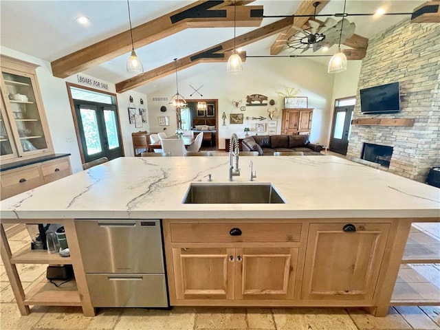 kitchen featuring hanging light fixtures, beam ceiling, a kitchen island with sink, and sink