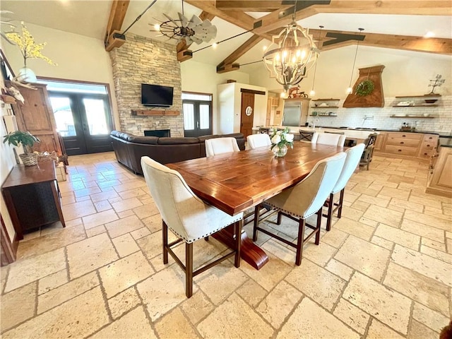 dining space with high vaulted ceiling, a chandelier, beamed ceiling, and a fireplace