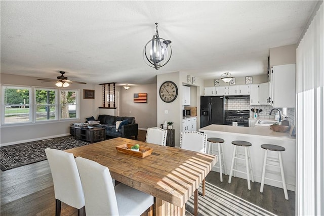 dining room with sink, ceiling fan with notable chandelier, and dark hardwood / wood-style flooring