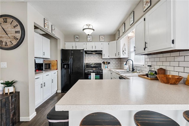 kitchen with black appliances, dark hardwood / wood-style flooring, kitchen peninsula, and a breakfast bar