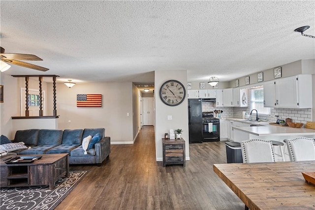 living room featuring dark hardwood / wood-style flooring, sink, ceiling fan, and a textured ceiling