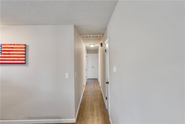 hall featuring wood-type flooring and a textured ceiling