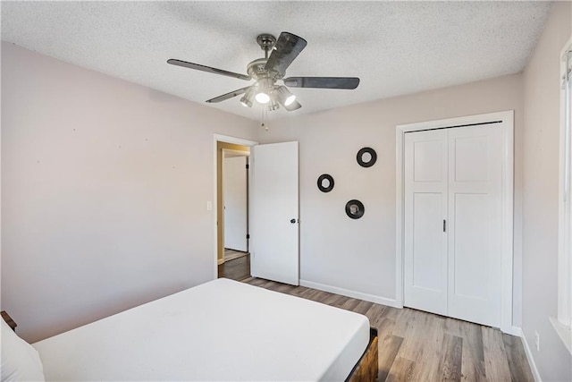 bedroom featuring a textured ceiling, ceiling fan, a closet, and light hardwood / wood-style floors