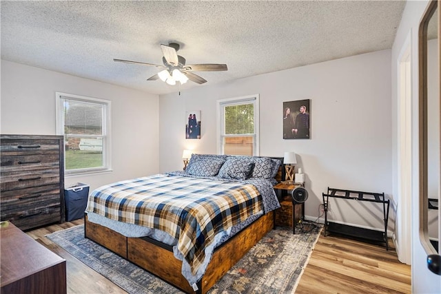 bedroom with a textured ceiling, ceiling fan, and light hardwood / wood-style floors