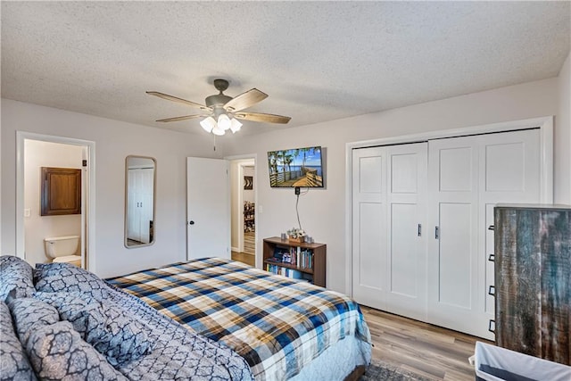 bedroom featuring ensuite bath, light hardwood / wood-style floors, a closet, ceiling fan, and a textured ceiling