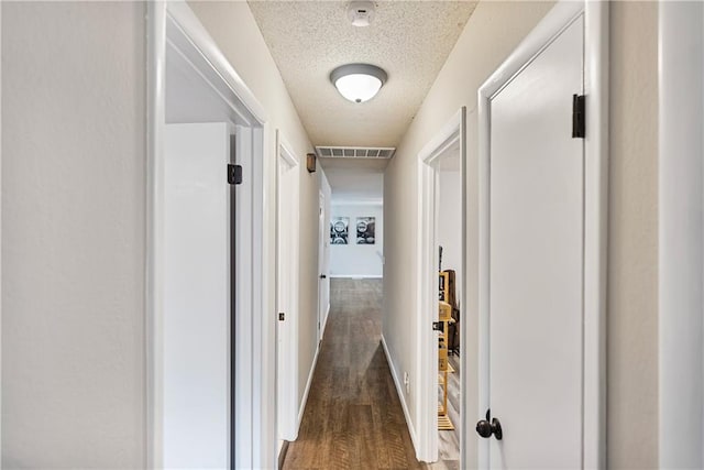 hallway with dark wood-type flooring and a textured ceiling