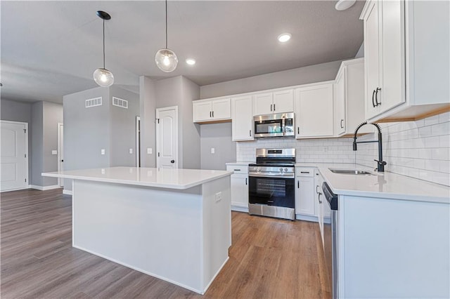 kitchen featuring white cabinetry, sink, stainless steel appliances, and a kitchen island