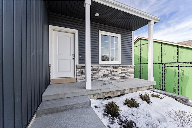 snow covered property entrance featuring covered porch