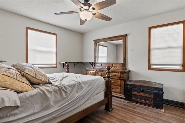 bedroom featuring dark wood-type flooring, ceiling fan, and multiple windows