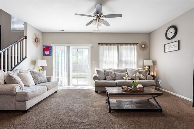 living area featuring a healthy amount of sunlight, baseboards, carpet, and a ceiling fan