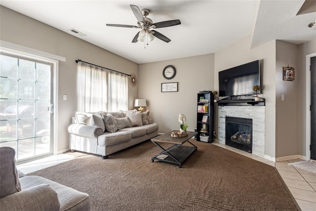 living area featuring visible vents, baseboards, ceiling fan, a fireplace, and tile patterned floors