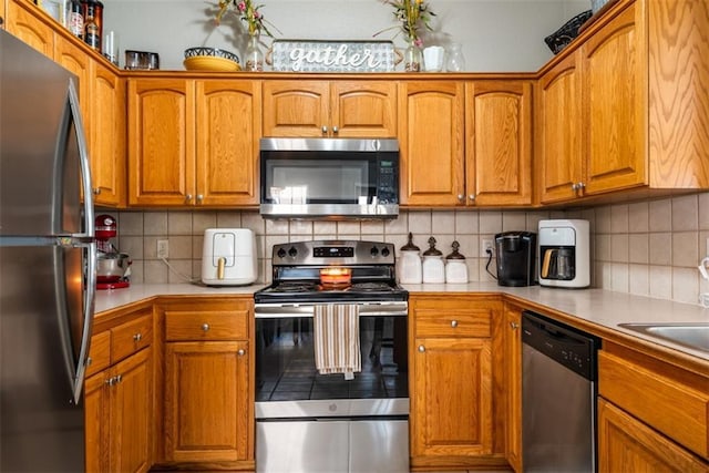 kitchen featuring stainless steel appliances, backsplash, brown cabinetry, and light countertops