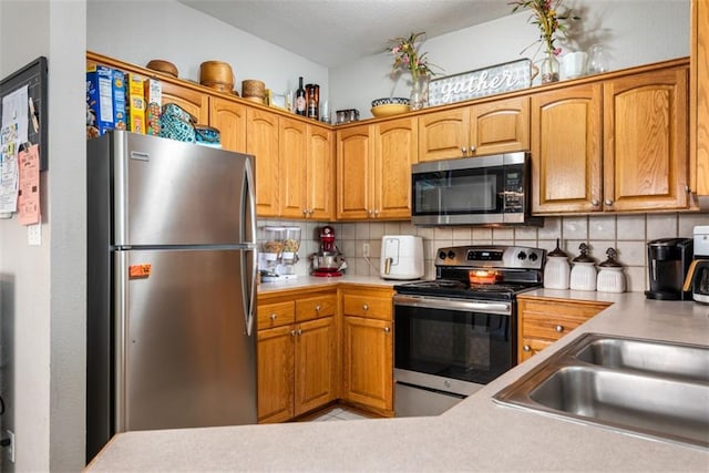 kitchen with decorative backsplash, light countertops, a sink, and stainless steel appliances