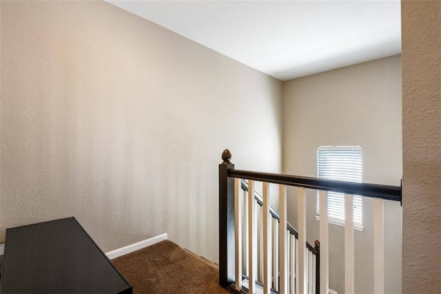 stairway with carpet flooring, baseboards, and a textured wall