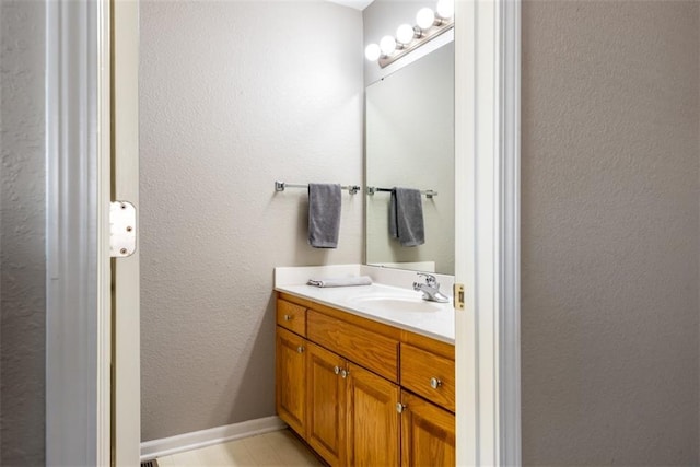 bathroom featuring vanity, baseboards, and a textured wall