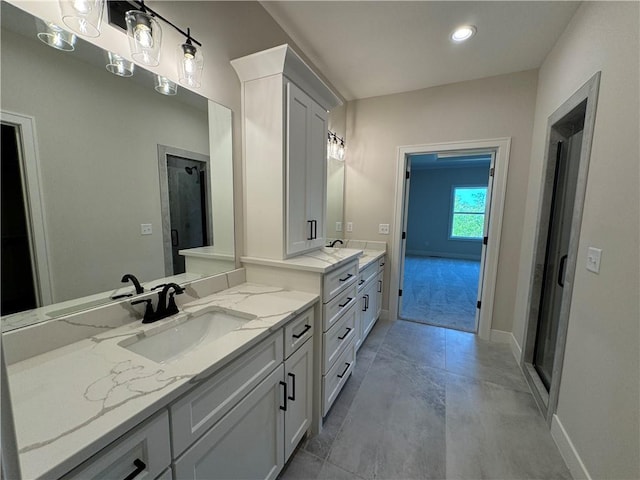 full bath with two vanities, baseboards, and a sink