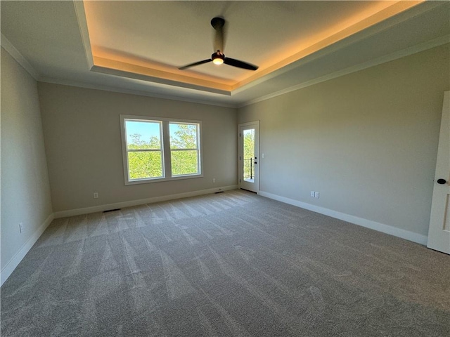 carpeted spare room with ceiling fan, a raised ceiling, visible vents, baseboards, and ornamental molding