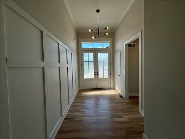 doorway with crown molding, baseboards, an inviting chandelier, dark wood-type flooring, and french doors