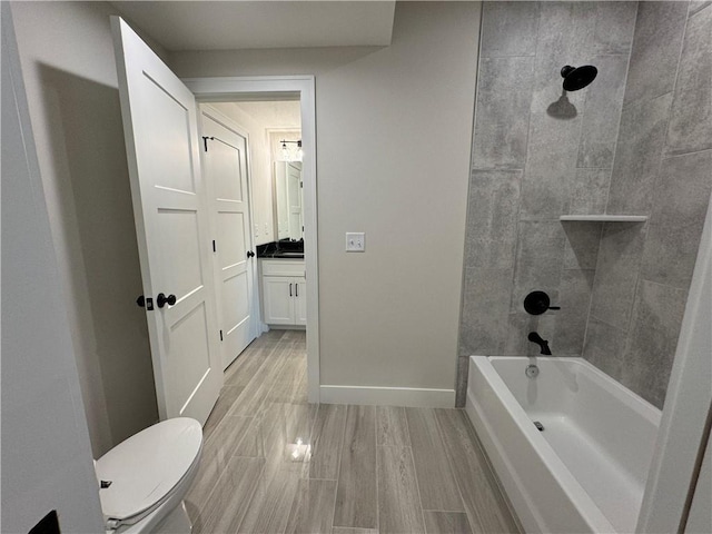 full bathroom with baseboards, toilet, wood finish floors, shower / bath combination, and vanity