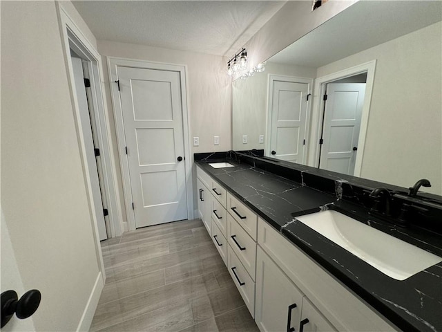 bathroom with baseboards, double vanity, and a sink