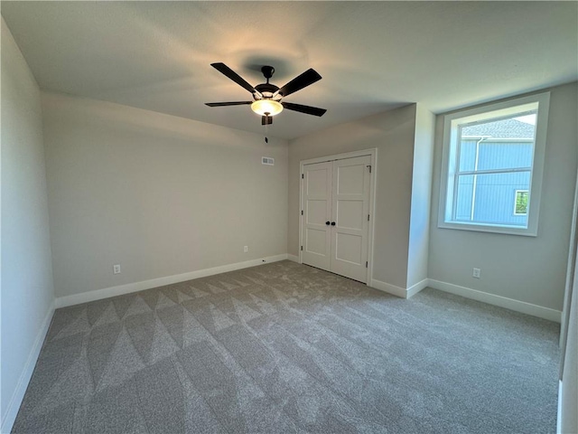 unfurnished bedroom featuring carpet floors, a closet, ceiling fan, baseboards, and visible vents