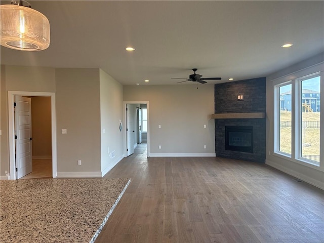 unfurnished living room featuring ceiling fan, hardwood / wood-style floors, and a fireplace