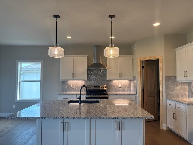 kitchen featuring sink, white cabinetry, pendant lighting, electric stove, and wall chimney range hood