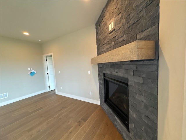 unfurnished living room featuring dark wood-type flooring and a large fireplace