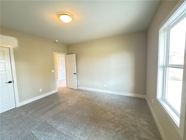 empty room with dark carpet and a wealth of natural light