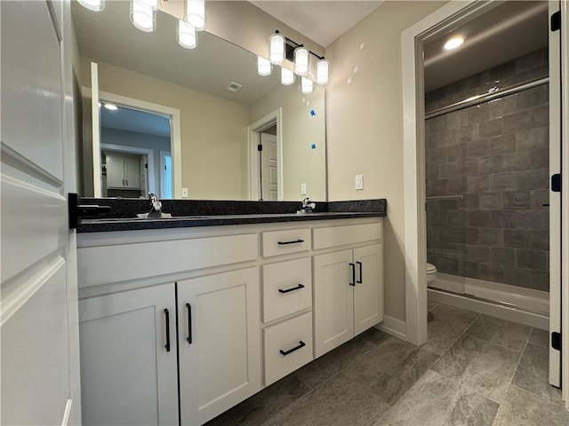 bathroom with vanity, a shower with door, and toilet