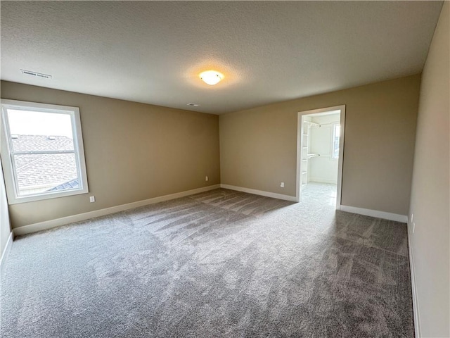 carpeted empty room with a textured ceiling