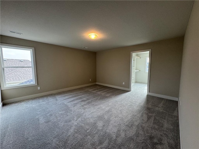 unfurnished room with carpet and a textured ceiling