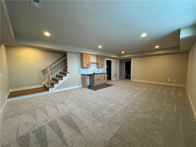 unfurnished living room with sink, light carpet, a textured ceiling, and a tray ceiling