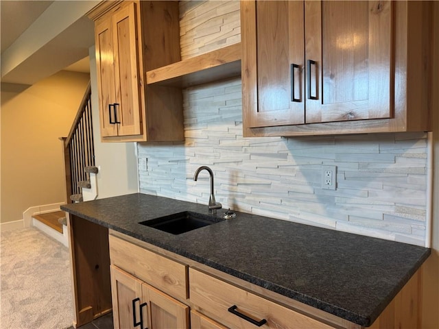 kitchen with dark stone countertops, sink, backsplash, and carpet floors