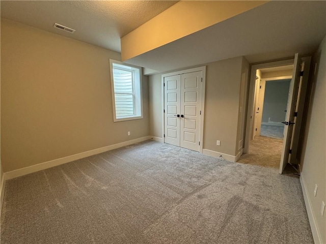 unfurnished bedroom featuring light colored carpet, a closet, and a textured ceiling