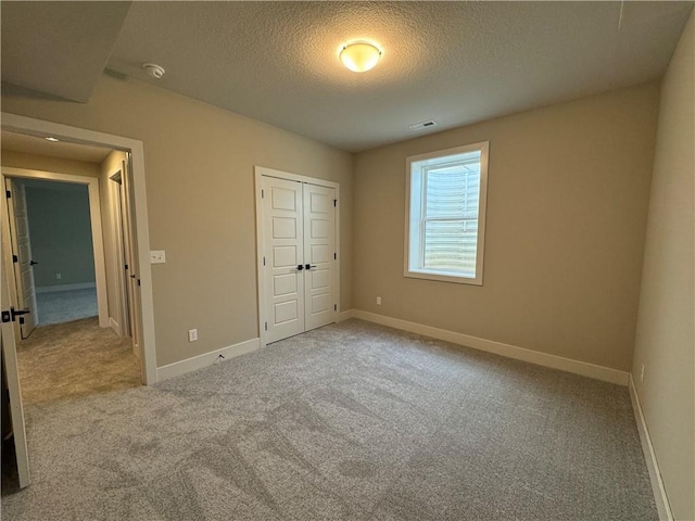 unfurnished bedroom with light colored carpet, a closet, and a textured ceiling