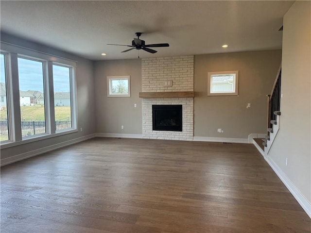 unfurnished living room featuring dark wood-type flooring, ceiling fan, and a fireplace