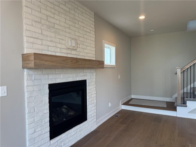 unfurnished living room featuring dark wood-type flooring and a fireplace