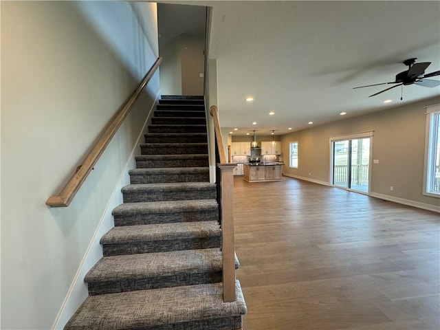 stairway with hardwood / wood-style flooring and ceiling fan